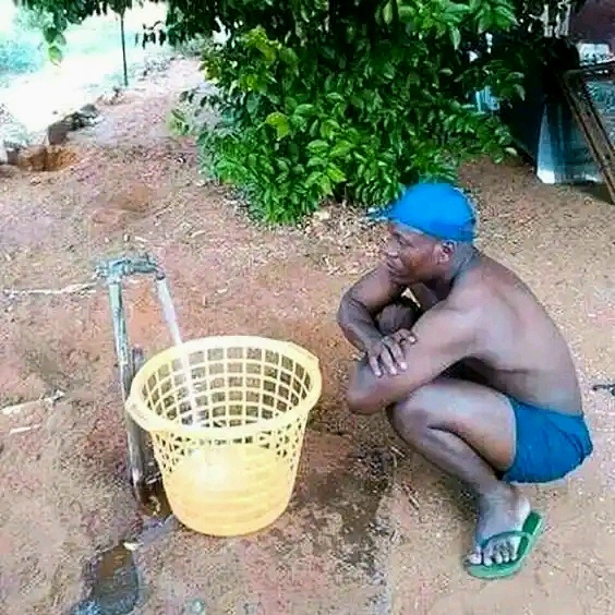 A man filling water in a dustbin like bucket 